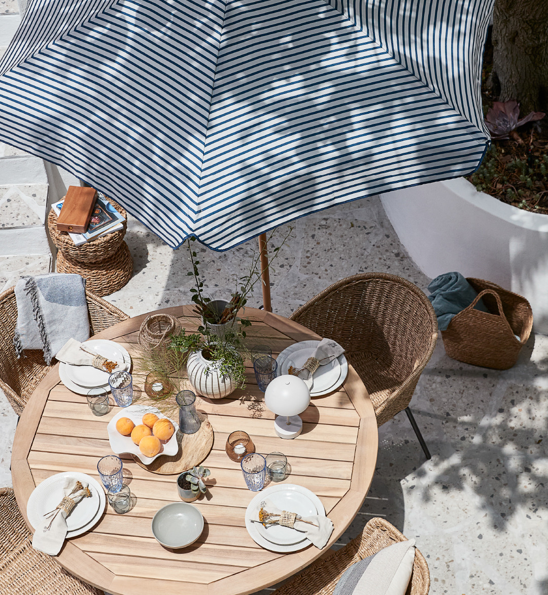 Terrasse avec table et chaises de jardin, parasol et vaisselle