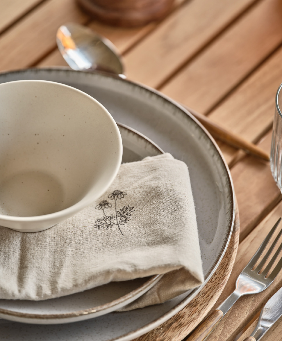 Vaisselle, assiettes, couverts, bol et serviette en tissu sur table de jardin